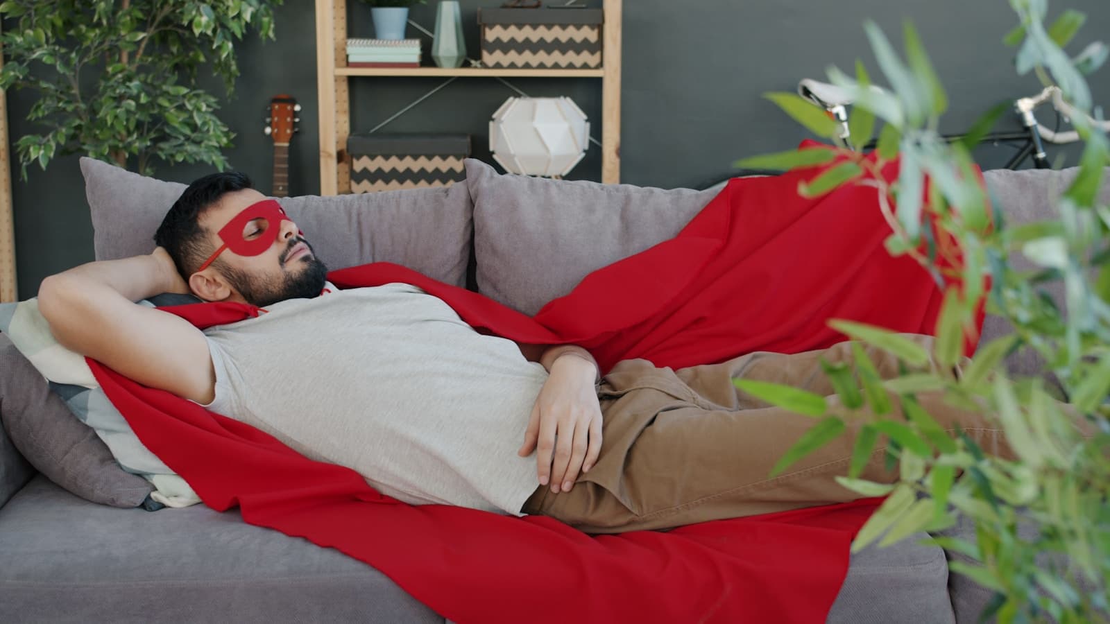Man in a superhero costume sleeping on a sofa